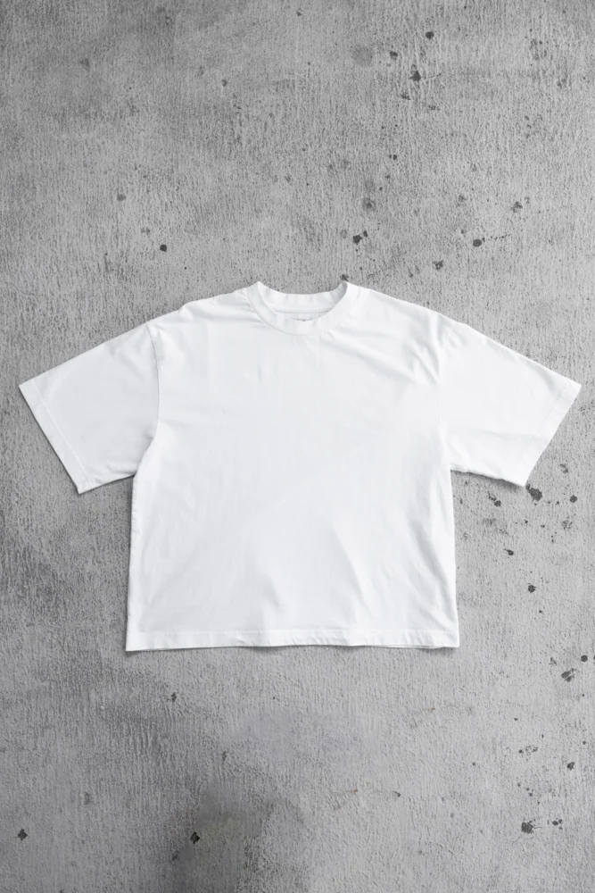 white t-shirt laid flat on concrete floor