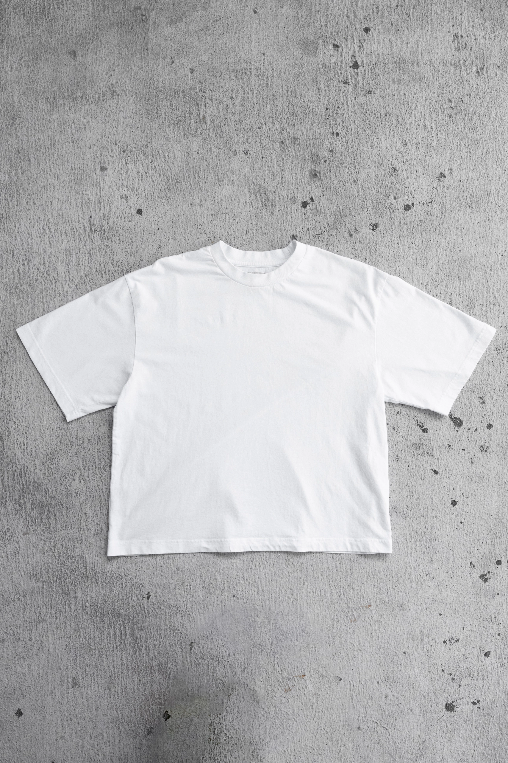 white t-shirt laid flat on concrete floor